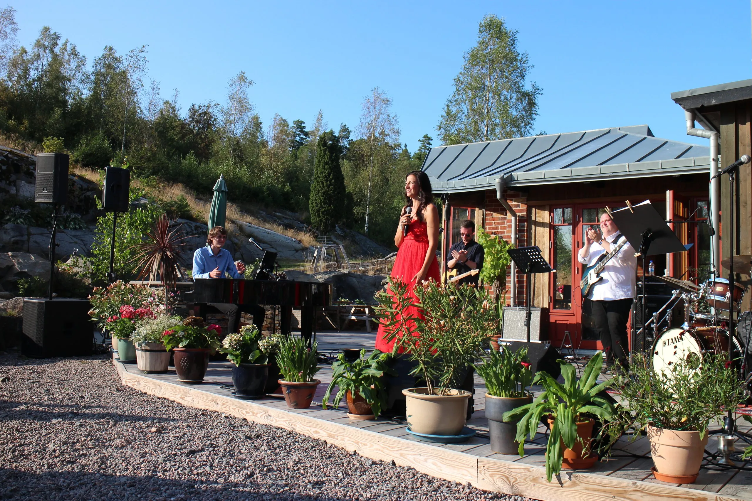 Konsert på terrassen vid huset, omgiven av blommor och krukväxter